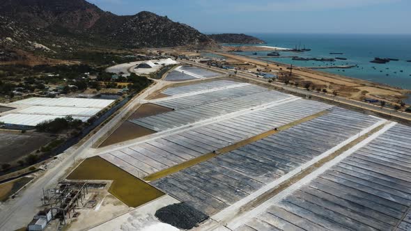 Massive salt fields near ocean coastline in Vietnam, aerial drone orbit view