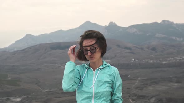 Young Woman Looking at Camera on Background of Mountain Valley