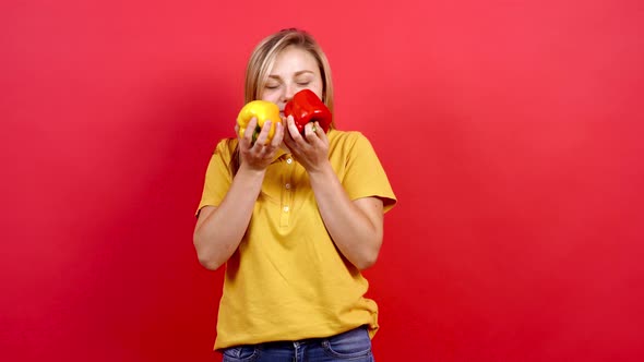 Cute and Slightly Fat Girl in a Yellow T-shirt Holding a Yellow and Red Pepper in Her Hand.