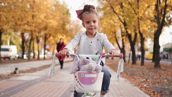 Little Girl Rides Bicycle on Autumn City Boulevard