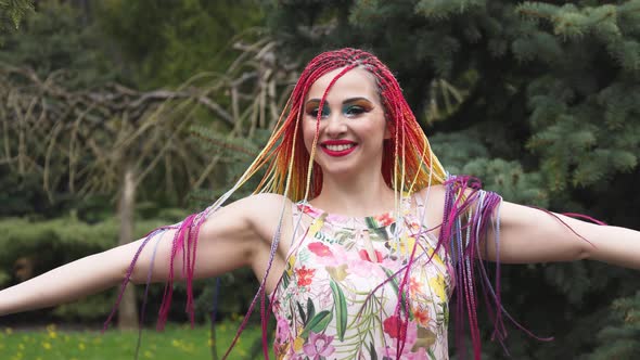 A Girl with a Happy Smile in a Dress with African Braids and Makeup Whirls and Throws Her Hair Up in