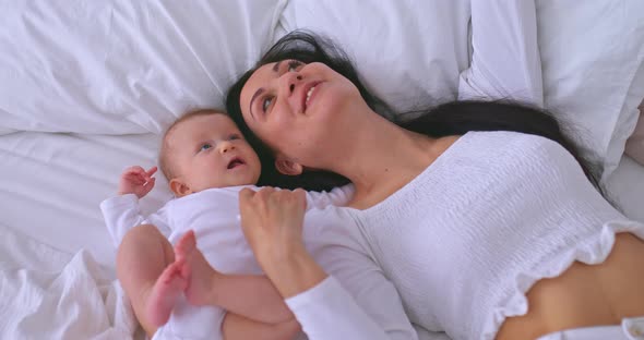 Portrait a Beautiful Mother with a Baby Take a Selfie and Smile They Lie on a White Bed