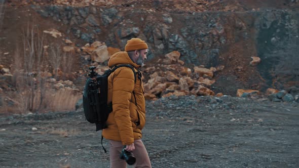 Bearded Traveler Photographer in Sunglasses and a Hat with a Reflex Camera in His Hands