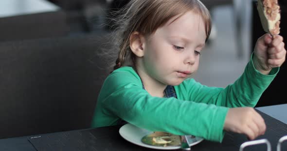 Pretty Little Child Eats Something Yummy in the Kitchen at Home