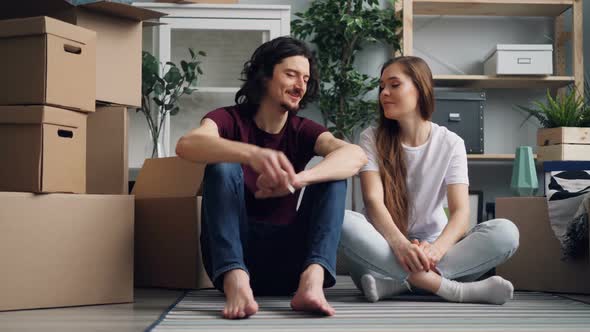 Young Man Giving Keys To Girlfriend Then Kissing Relaxing on Floor with Boxes