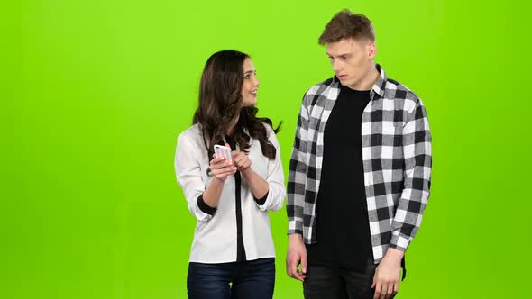 Loving Guy and Girl Look in the Phone and Choose Common Pictures. Green Screen