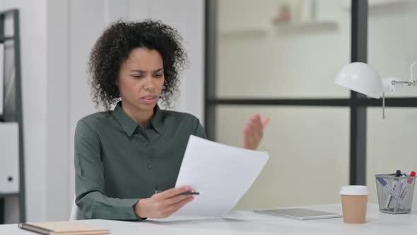 African Woman Reacting to Loss While Reading Papers