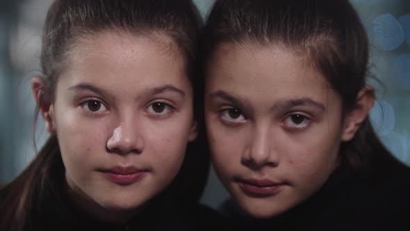 Little Girl Twins Raise Their Heads and Look Into the Camera