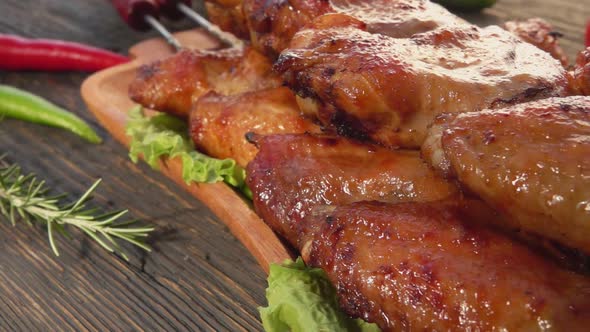 Panorama of Delicious Grilled Chicken Wings on the Skewers on the Wooden Plate
