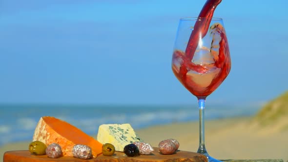 Red Wine Is Poured Into Glass Near Cheese and Olives