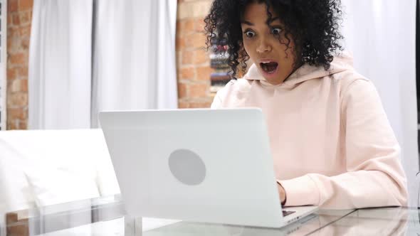 Excited AfroAmerican Woman Celebrating Success While Working on Laptop Sitting on Couch