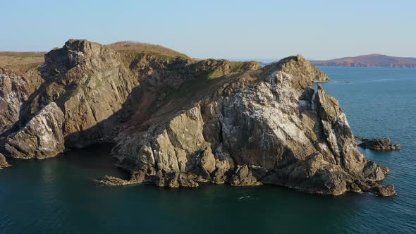 Island with High Vertical Rocks Among the Sea
