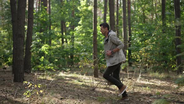 Wide Shot Caucasian Man Running with Backpack in Summer Forest Outdoors