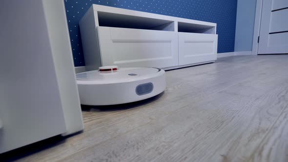 A Robotic Vacuum Moves Along Several Pieces of White Furniture