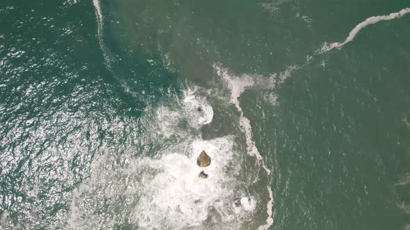 Vertical straight down view of beautiful sea water crashing on rocks at Nazare, Portugal.