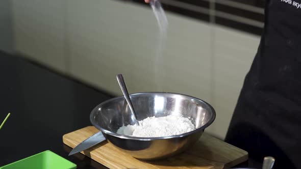 Male hands adding salt into the flour