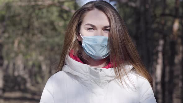 Close-up Portrait of Brunette Grey-eyed Caucasian Woman in Protective Face Mask Standing Outdoors