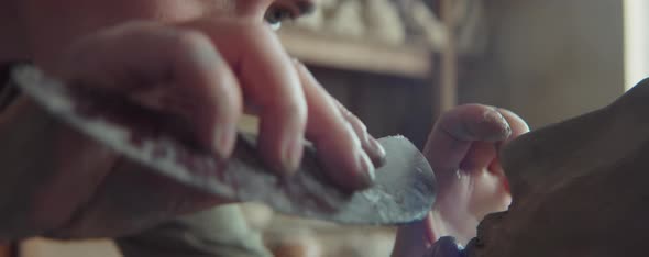 Young Female Sculptor Shaping Clay Head with Tool