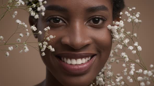 African American Woman Smiling Posing With White Flowers Beige Background