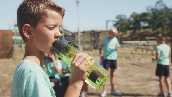 Caucasian boy drinking water at boot camp