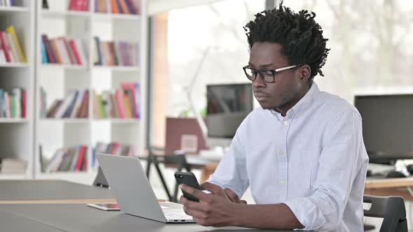 African Man Using Smartphone and Laptop