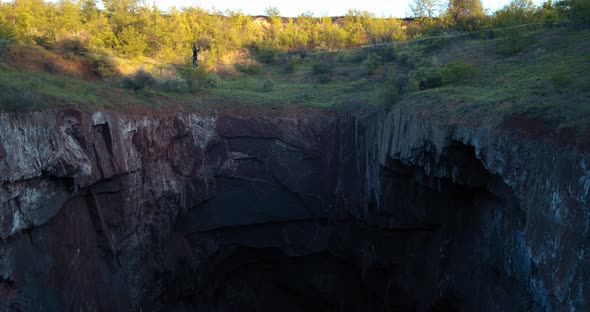 Stunning View on a Huge Natural Quarry and a Man Walking on the Slackline