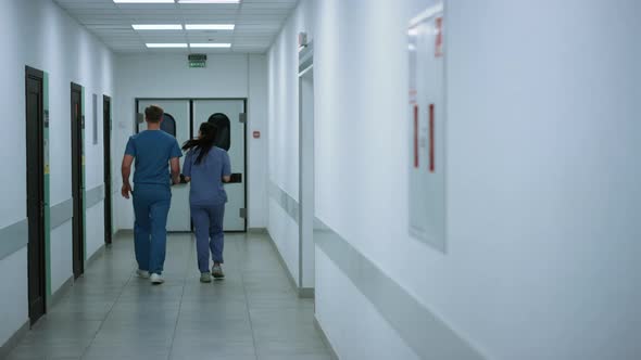 Unknown Doctor Nurse Moving Down Hallway Back View