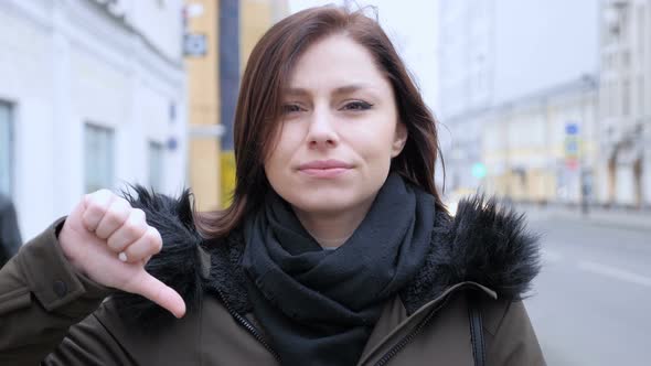 Thumbs Down by Young Woman on Street