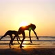 Silhouette of Sporty Young Women Practicing Acrobatic Element on the Beach - VideoHive Item for Sale