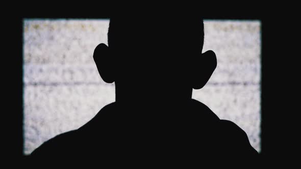 Silhouette of an Anonymous Man's Head Is Watching White Static Noise and TV Interference