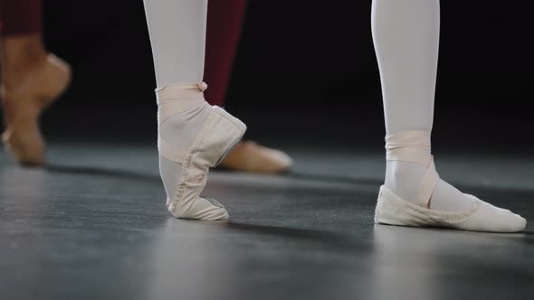 Two Pairs of Female Legs on Floor on Performance Stage in Dance Class Studio Do Ballet Exercises