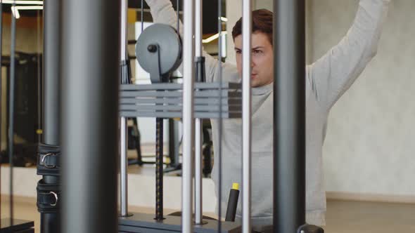 Young Man in Gray Hoodie Training Arms in a Gym