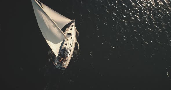 Top Down of Yacht Under White Sail at Dark Open Sea Aerial. Ocean Bay Black Water and Lone Sailboat