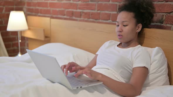 African Woman Having Wrist Pain Working on Laptop in Bed