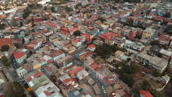 Aerial lowering over charming colorful houses revealing Valparaiso hillside city in background from