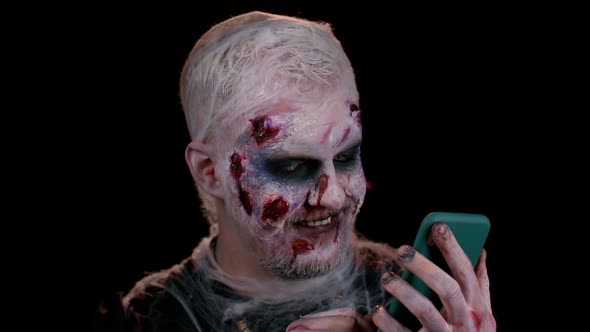 Frightening Man Halloween Zombie Using Mobile Phone Typing New Post on Web Browsing Addiction