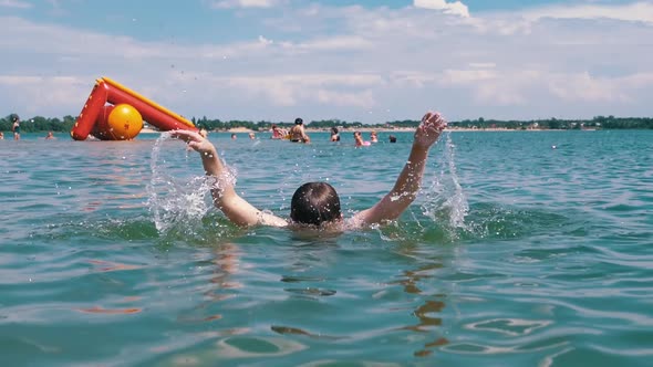 Happy Child Swimming Splashing Diving Underwater on the Beach in Sunlight