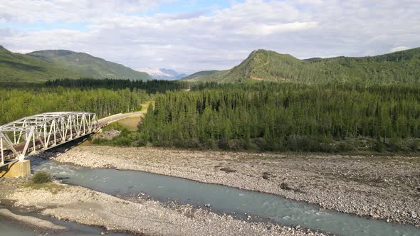 Drone view of a bridge that crosses Toad river and a trail in the woods of northern British Columbia