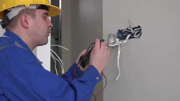 Man with Helmet Testing Socket with Voltmeter