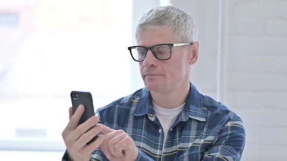 Portrait of Cheerful Casual Middle Aged Man Using Smartphone