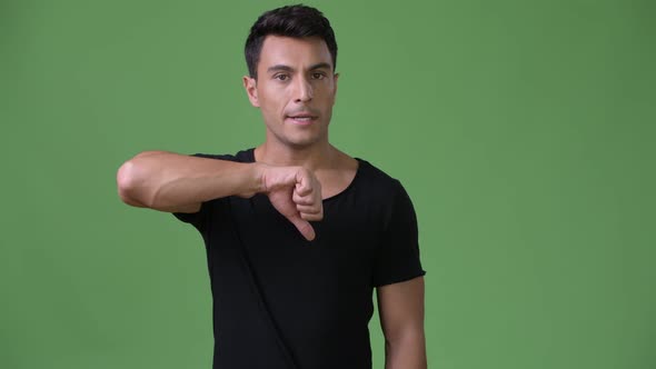 Young Handsome Hispanic Man Against Green Background