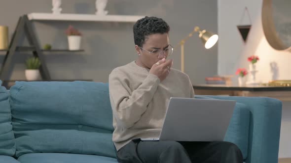 African Woman with Laptop Coughing on Sofa