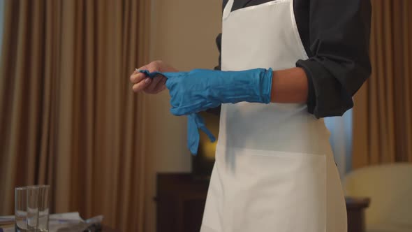 Housemaid Put on Protective Gloves in Hotel Room 