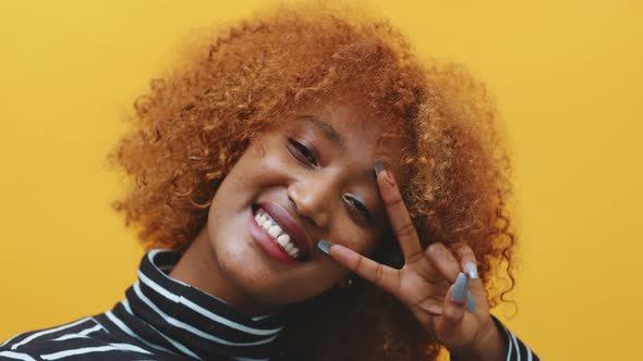 Young African American Black Woman with Curly Afro Hair and Long Nails Posing in Front of Yellow