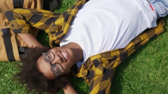 Top View of Afroamerican Young Man Lying on Green Grass and Looking at Camera