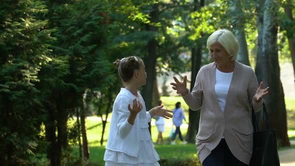 Little Girl Walking With Granny and Telling Her Stories From School Life, Trust