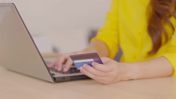 Close up hand of young woman using credit card for pay online shopping on computer laptop