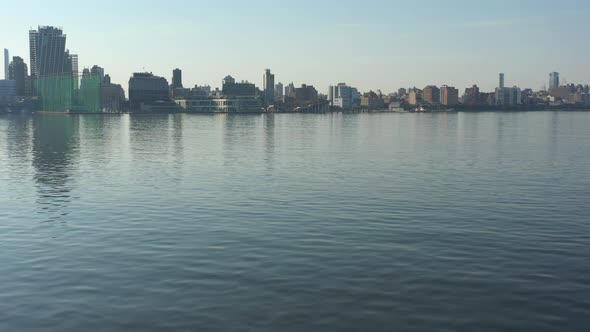 A low angle drone shot over a calm Hudson River at sunrise. The camera dolly in over the water flyin