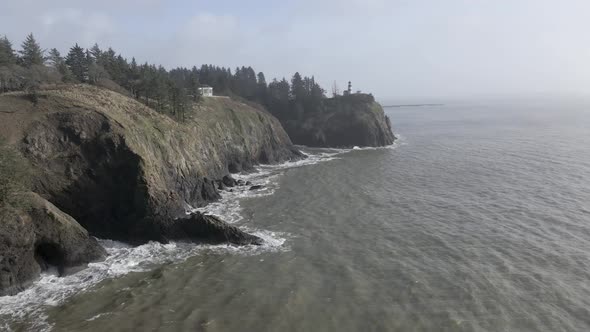 Cape Disappointment lighthouse sits on a jagged bluff high above the turbulent ocean, aerial trackba