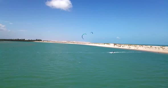 Aerial drone view of a man kiteboarding on a kite board in a lagoon lake.